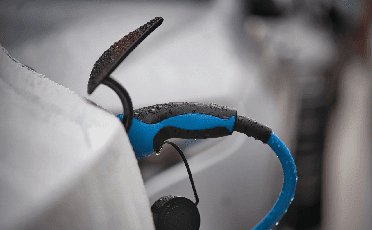 De afbeelding toont een close-up van een stekker voor een elektrische auto. 