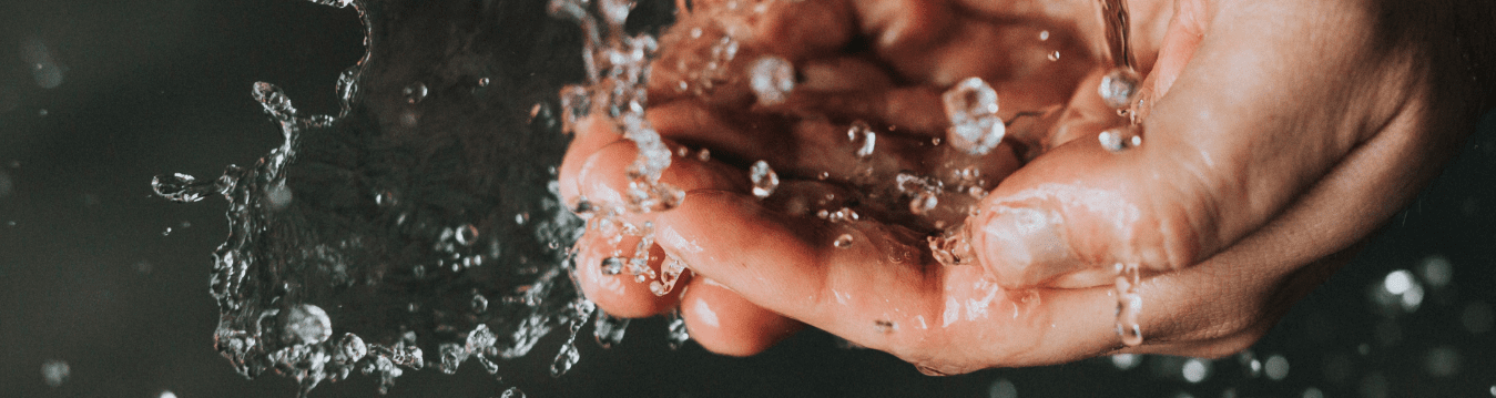 De afbeelding toont een close-up van handen die schoon water opvangen.